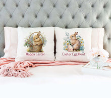 Load image into Gallery viewer, Two Easter pillow covers on a bed. One pillow cover features a bunny in an Easter basket with flowers. Below the image are the words &quot;Happy Easter.&quot; The other pillow cover features a bunny with some flowers and an Easter egg. Below the image are the words &quot;Easter Egg Hunt.&quot;
