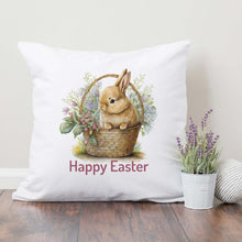 Load image into Gallery viewer, A Easter pillow cover with an Easter Bunny in a basket surrounded by flowers with the words &quot;Happy Easter&quot; printed below it. 
